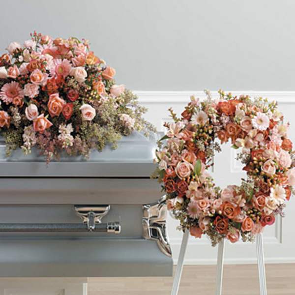 Peach and pink floral casket spray with a matching wreath on a gray casket