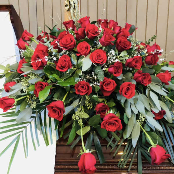 Large arrangement of red roses with greenery in a wooden casket spray