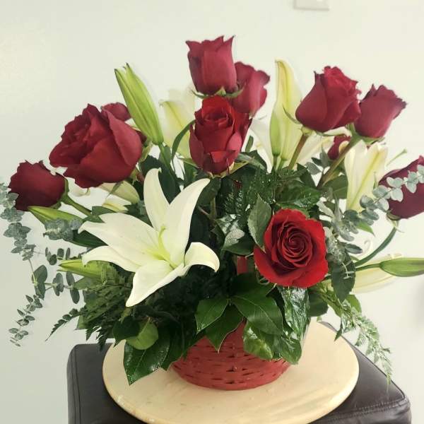 Red roses and white lilies in a red basket arrangement