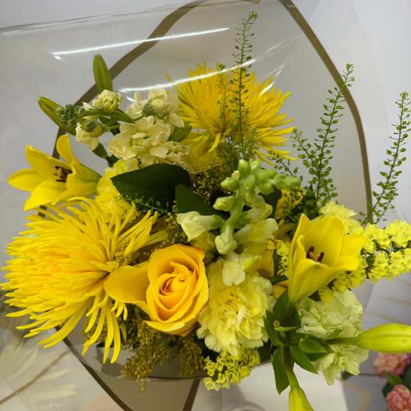 Yellow bouquet with lilies, roses, and chrysanthemums wrapped in clear paper