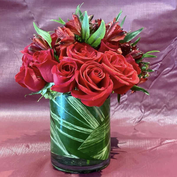 Red roses arranged in a green glass vase