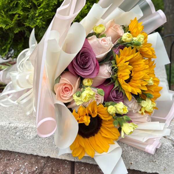 Bouquet of roses and sunflowers wrapped in pale pink and white paper