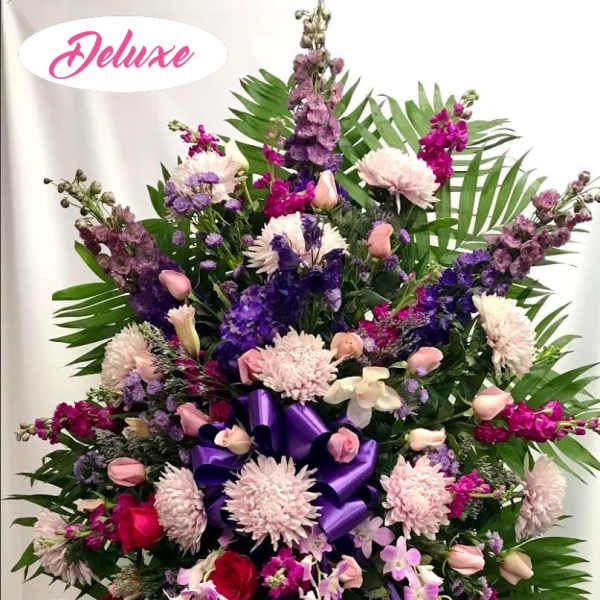Large standing floral spray with purple and pink flowers and ribbon