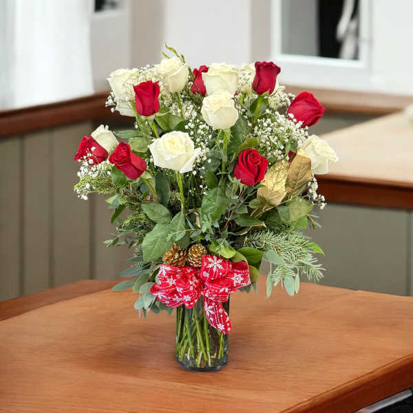 Red and white roses in a glass vase with a red ribbon
