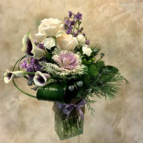 Bouquet of white roses and purple calla lilies in a glass vase