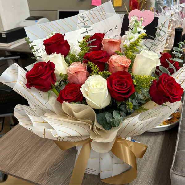 Bouquet of red, white, and blush roses wrapped in patterned paper