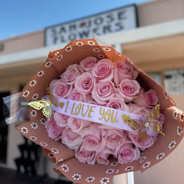 Bouquet of pink roses wrapped in patterned paper with an "I LOVE YOU" ribbon
