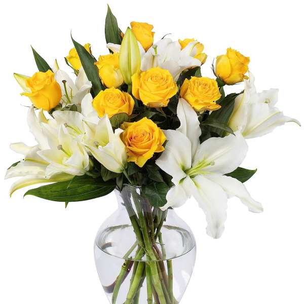 Yellow roses and white lilies arranged in a clear glass vase