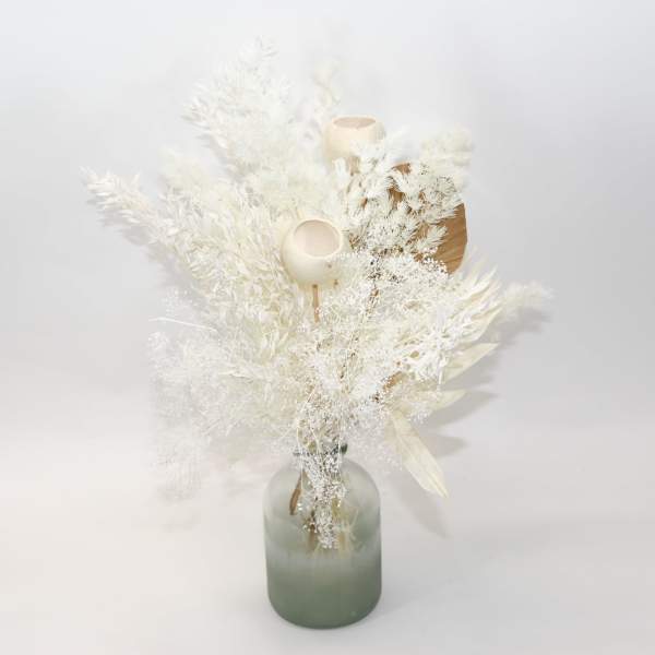 White dried floral arrangement in a frosted glass vase