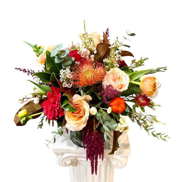 Mixed bouquet with peach and red flowers in a glass vase