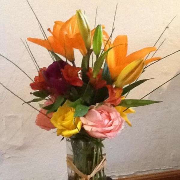 Colorful bouquet of lilies and roses in a glass vase