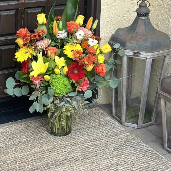 Colorful mixed bouquet in a glass vase with yellow, orange, red, and white flowers