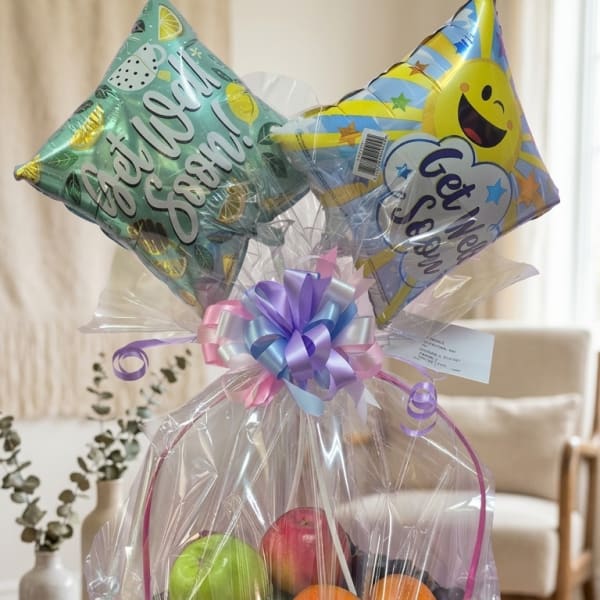 Fruit basket wrapped in clear cellophane with two star balloons on top.