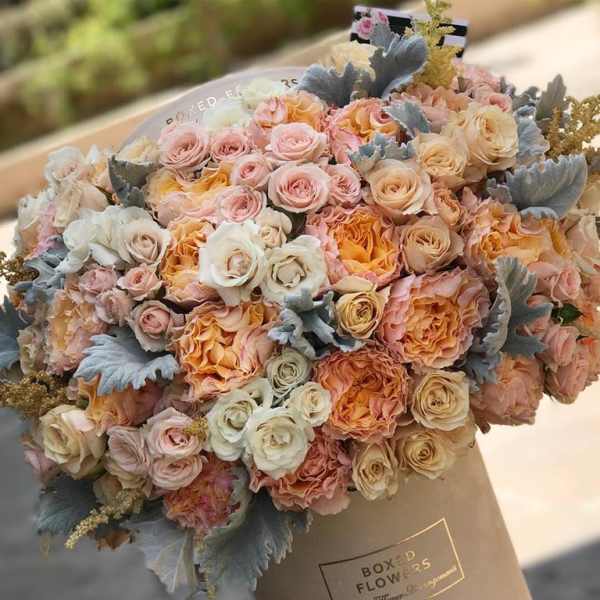 Large bouquet of blush, peach, and cream roses in a wrapped box