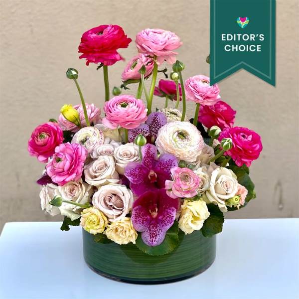 Pink and white floral arrangement in a green glass vase
