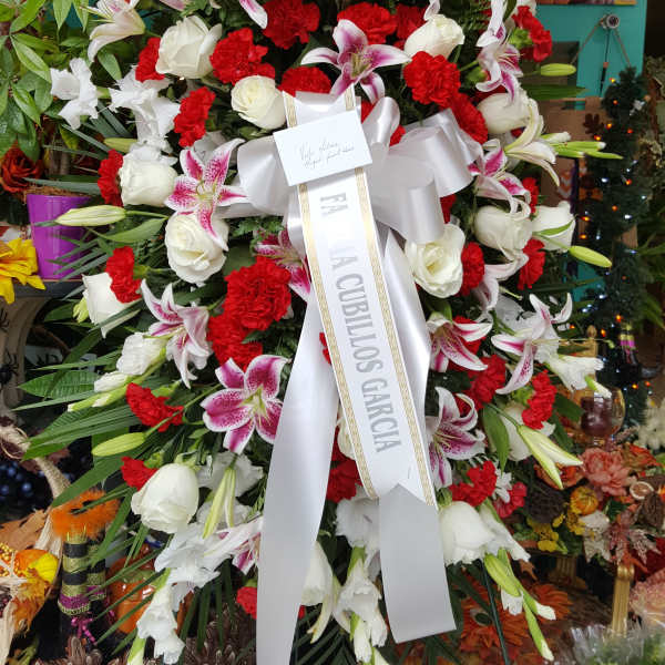 Large funeral wreath of red, white, and pink flowers with a white ribbon