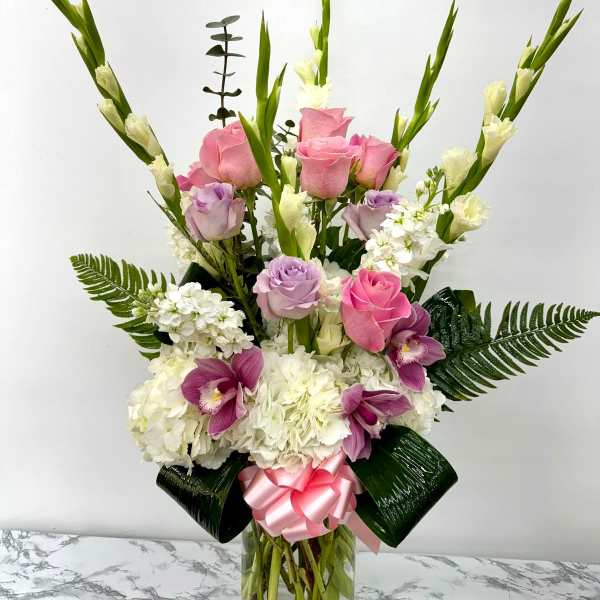 Pink and lavender roses with white flowers in a glass vase