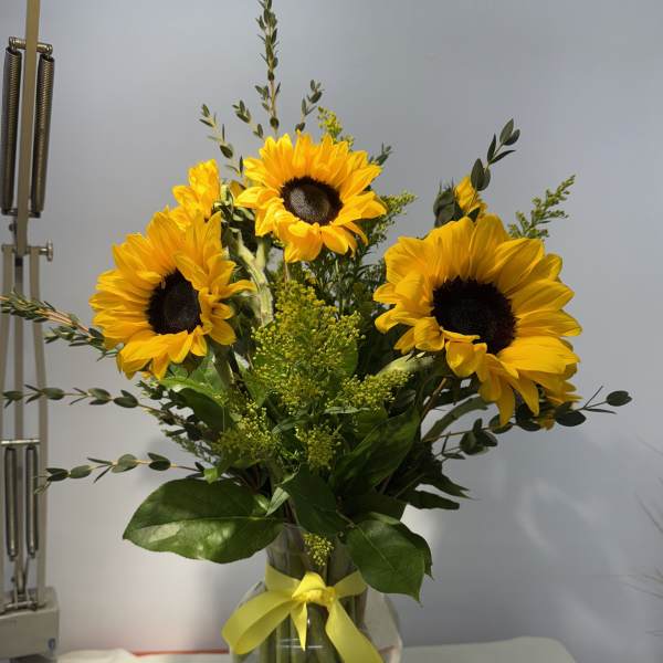 Sunflower bouquet in a glass vase with a yellow ribbon