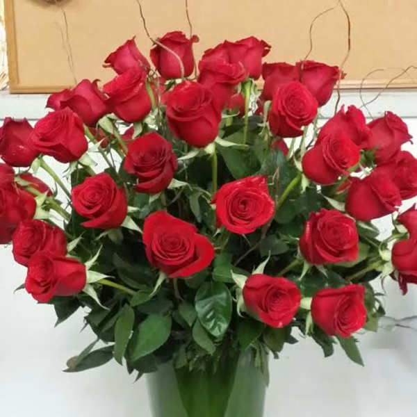 Red roses arranged in a tall glass vase