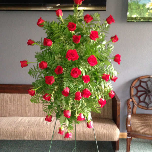 Tall standing arrangement of red roses and greenery on a metal easel