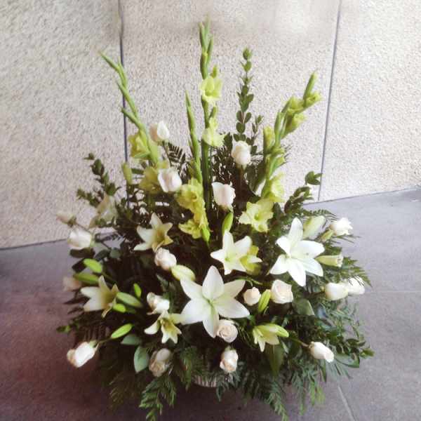 White lilies and pale green gladiolus in a low floral arrangement.