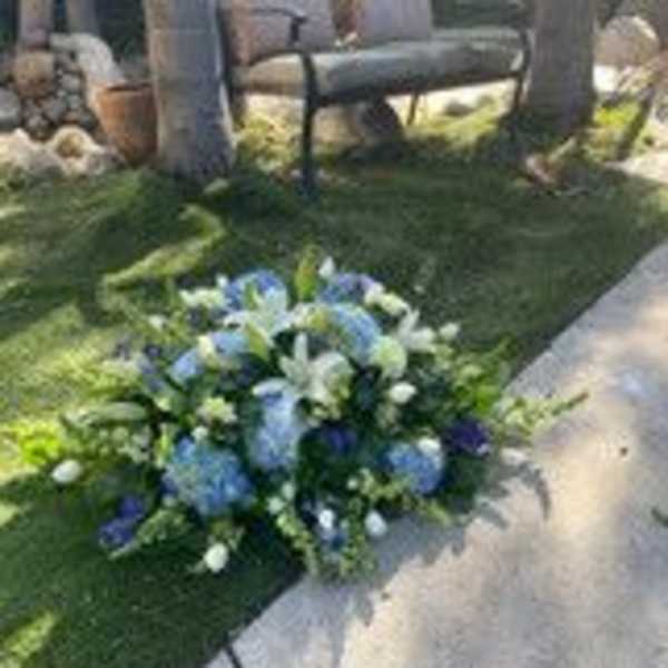 Blue and white floral arrangement placed beside a walkway outdoors