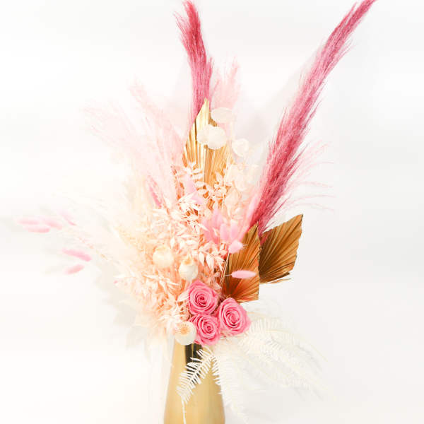 Pink roses and dried pampas-style stems in a gold vase
