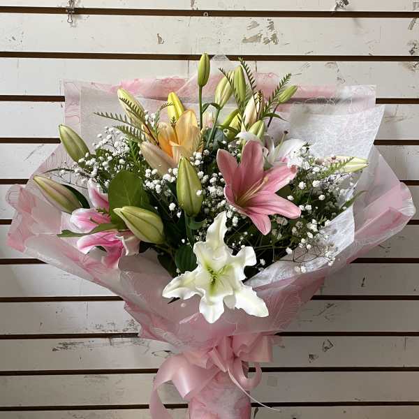 Bouquet of pink, white, and yellow lilies wrapped in pink paper