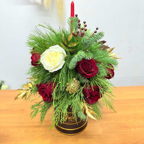 Holiday arrangement of red and white roses in a black container with a red candle