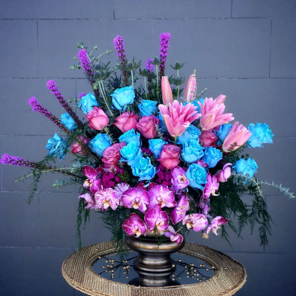 Large bouquet of blue and pink roses with pink lilies and orchids in a dark vase