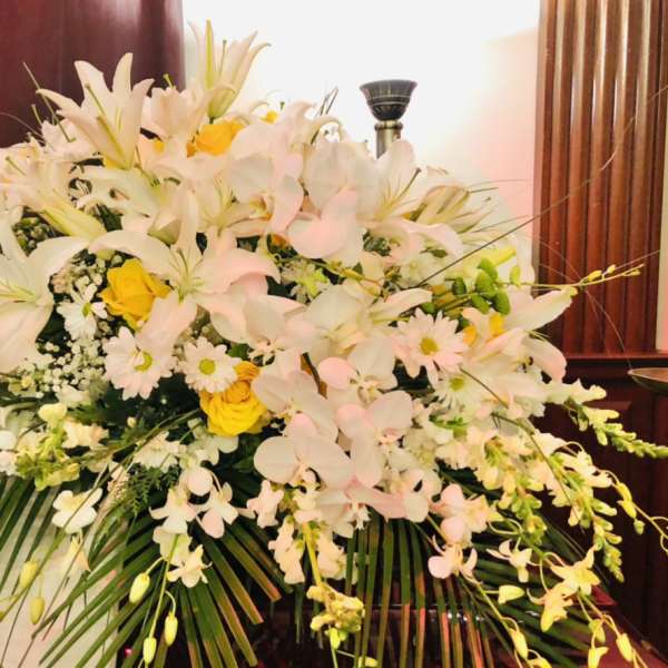 Large white and yellow floral arrangement with lilies and orchids