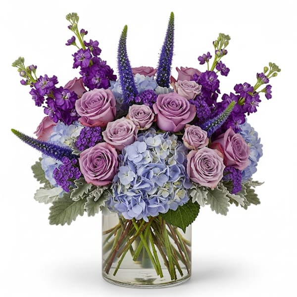 Lavender roses and blue hydrangeas in a clear glass vase