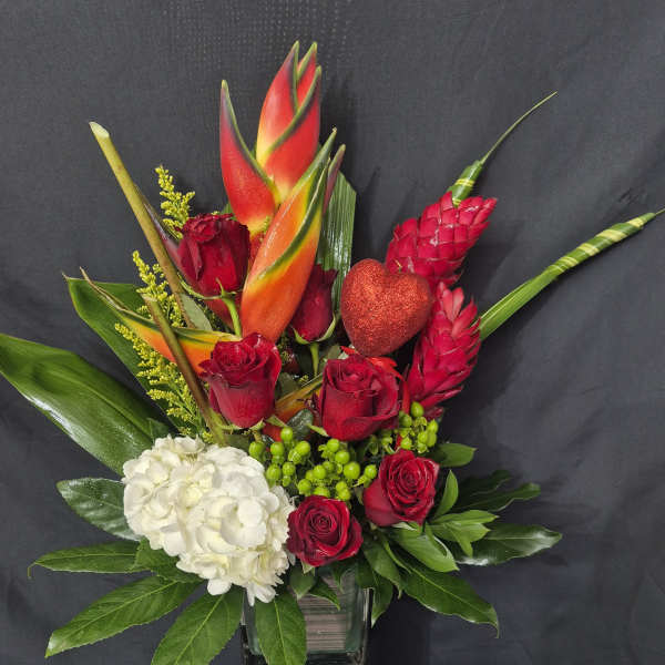 Red roses and white hydrangea in a glass vase with tropical blooms and a glitter heart