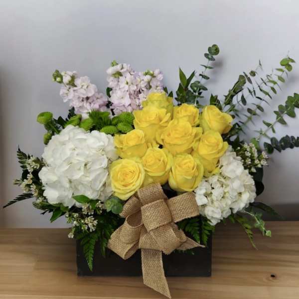 Yellow roses and white hydrangeas in a black box with a burlap bow