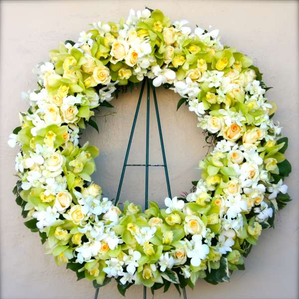 Large floral wreath of white and pale yellow flowers on a stand