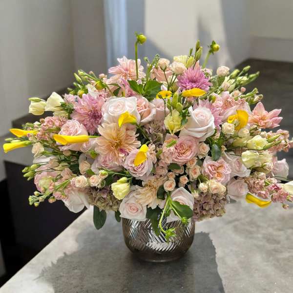Pink and white floral arrangement in a glass vase with yellow accents