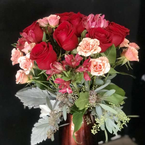 Bouquet of red roses and pink carnations in a tall vase