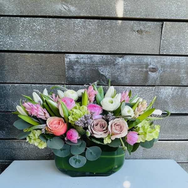 Mixed pink and white flower arrangement in a green glass vase