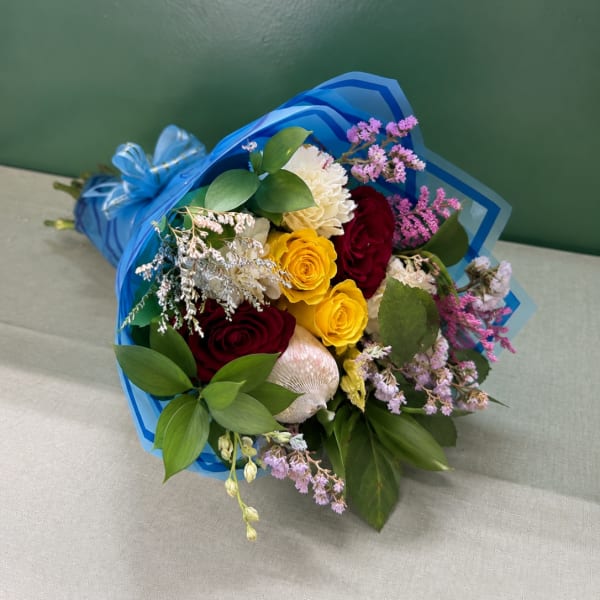 Bouquet of red, yellow, and white roses wrapped in blue paper