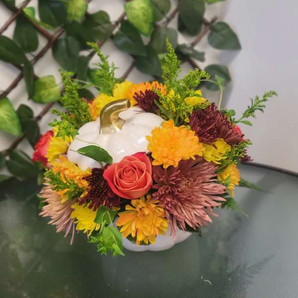 Pumpkin-shaped floral arrangement with a white pumpkin and mixed autumn flowers