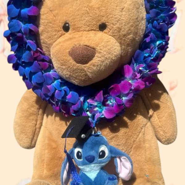 Teddy bear with a blue-purple flower lei and a small plush character hanging from it