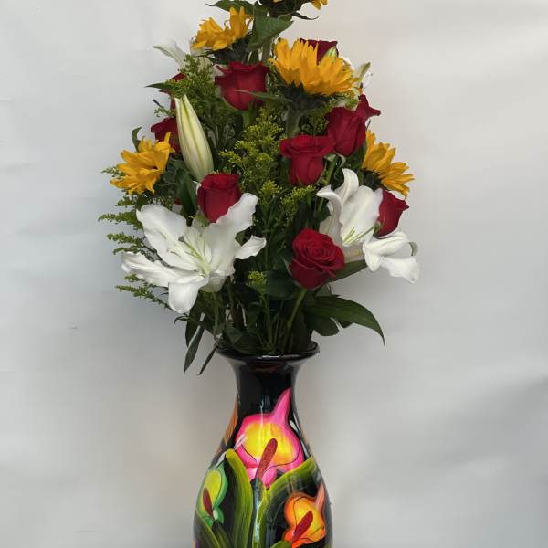 Tall bouquet of red roses, white lilies, and yellow sunflowers in a painted vase