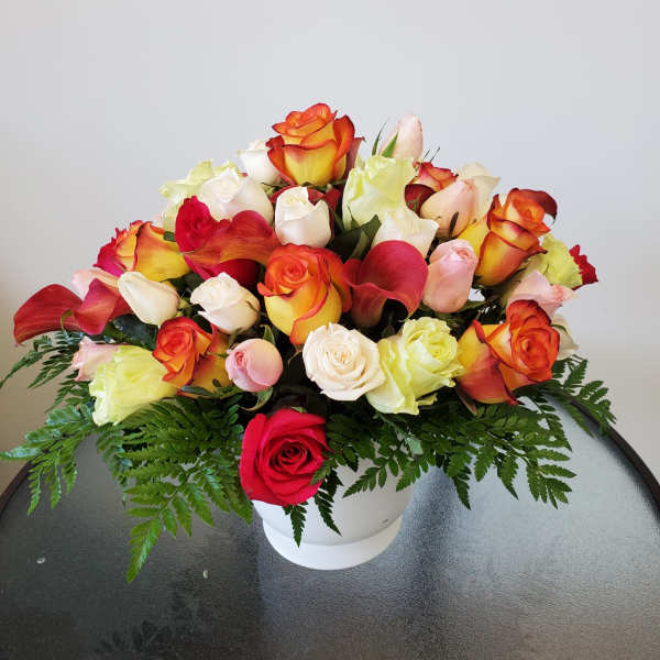 Mixed roses and calla lilies arranged in a white vase