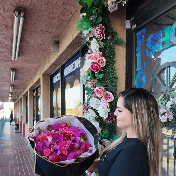 Woman holding a large bouquet of pink flowers wrapped in black paper