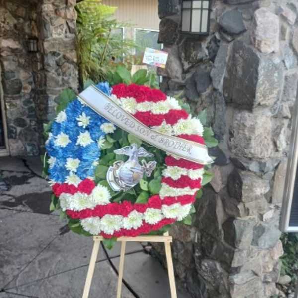 Patriotic floral wreath on an easel with red, white, and blue flowers