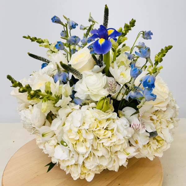 White and blue floral arrangement with roses and iris on a round table