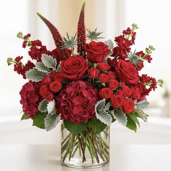 Red roses and hydrangeas in a clear glass vase
