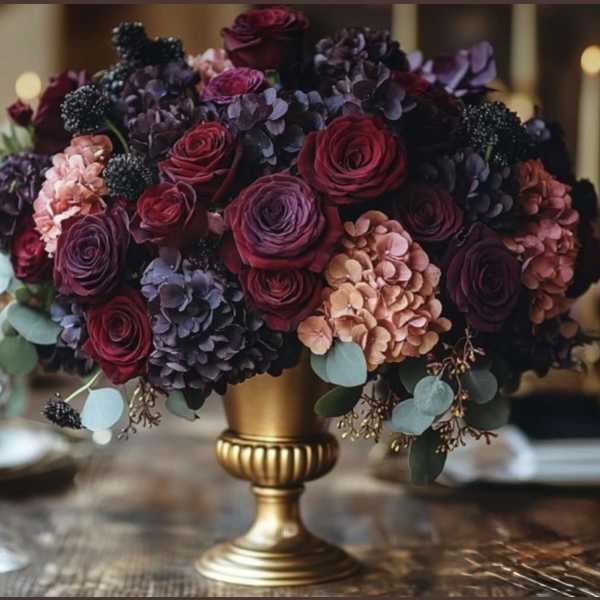 Deep red and purple floral arrangement in a gold pedestal vase