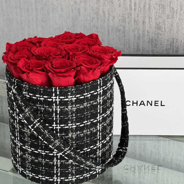 Red roses arranged in a black tweed-style round box with a handle