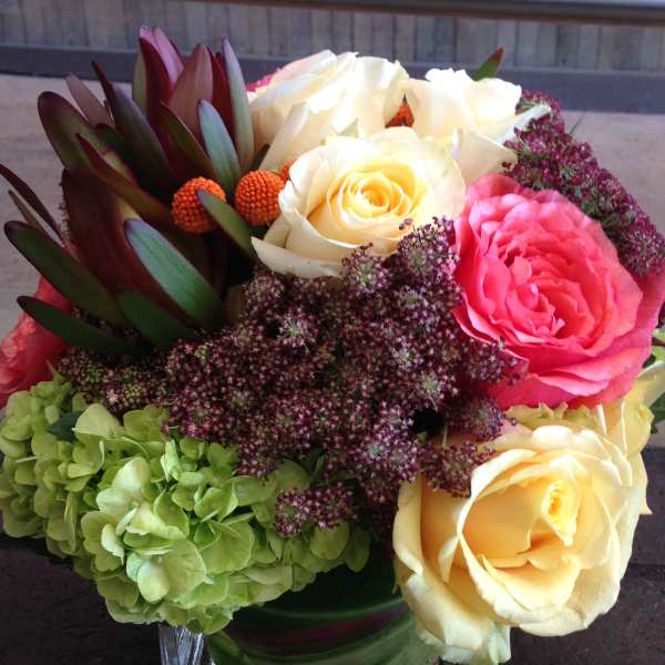Bouquet of cream and pink roses with green hydrangea in a glass vase